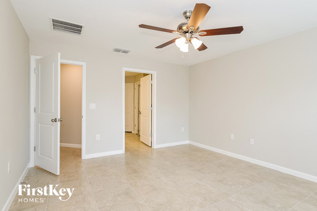 a living room with a ceiling fan and a door to a hallway