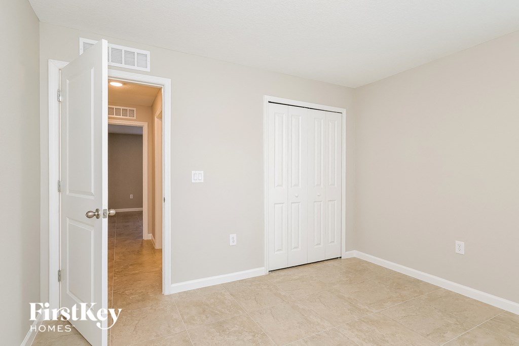 a bedroom with a door to a hallway and a closet