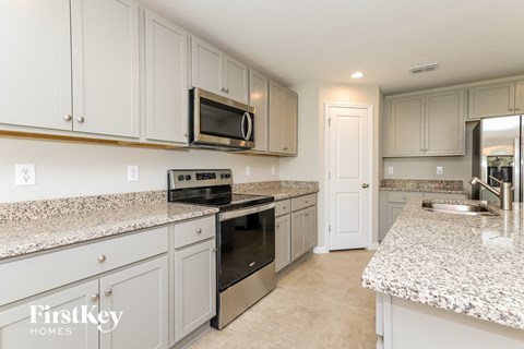A kitchen with a granite countertop and a microwave above it.