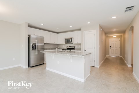 a large kitchen with an island and stainless steel refrigerator