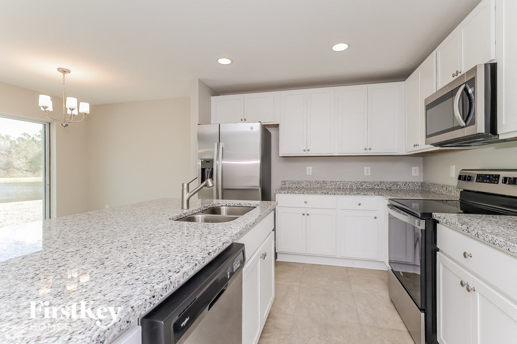 a white kitchen with granite counter tops and stainless steel appliances