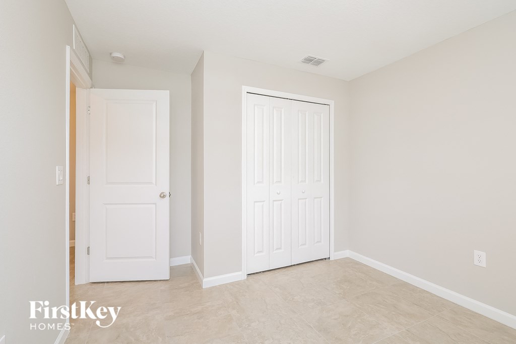 a bedroom with two white doors and a tiled floor