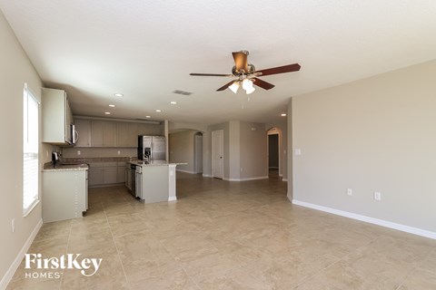 A spacious kitchen and living room with a ceiling fan.