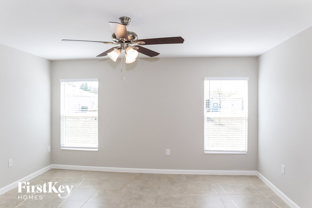 A room with a ceiling fan and two windows.