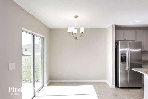 A kitchen with a refrigerator, cabinets, and a chandelier.