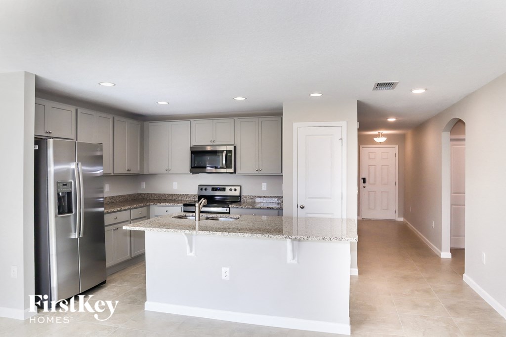 A kitchen with a white island and stainless steel appliances.