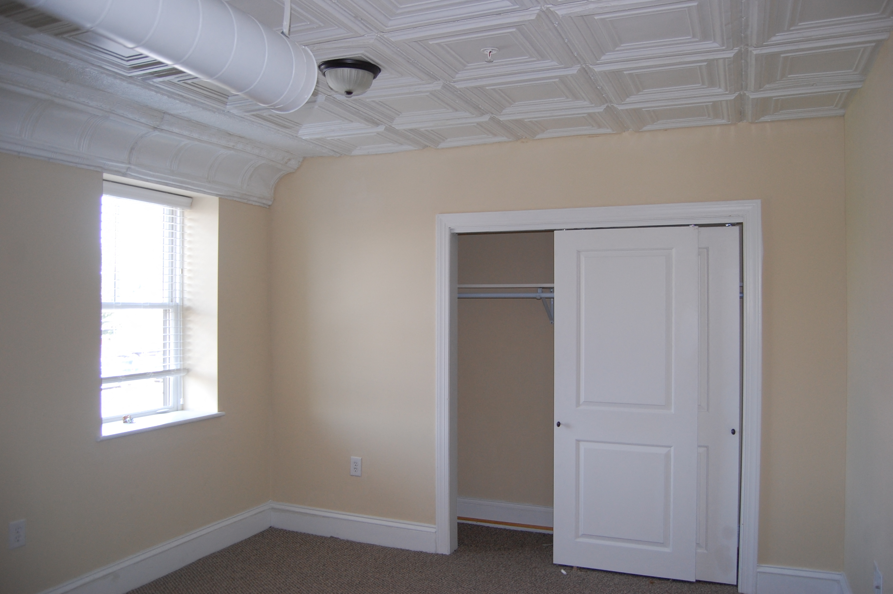 a bedroom with a closet and a window and a white door