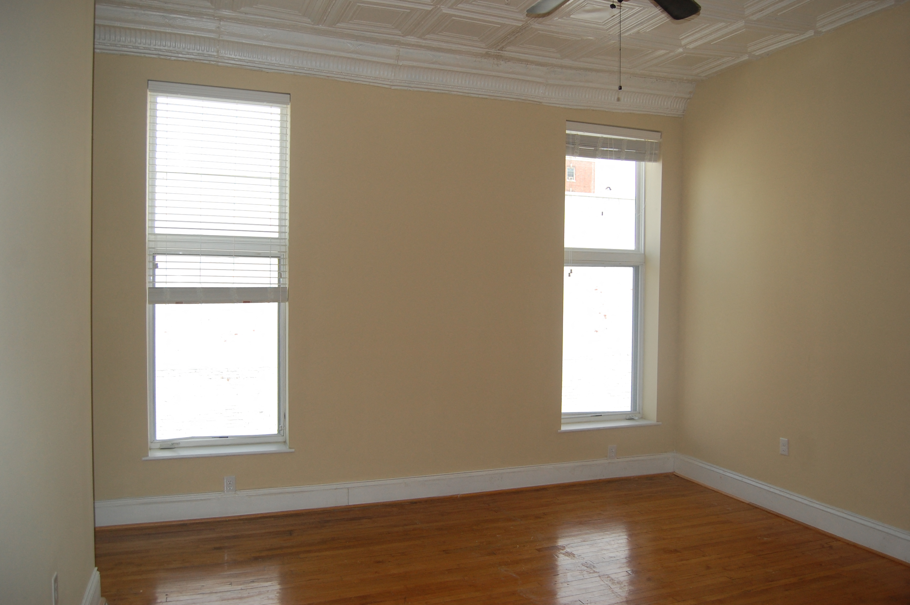 an empty room with two windows and a wood floor