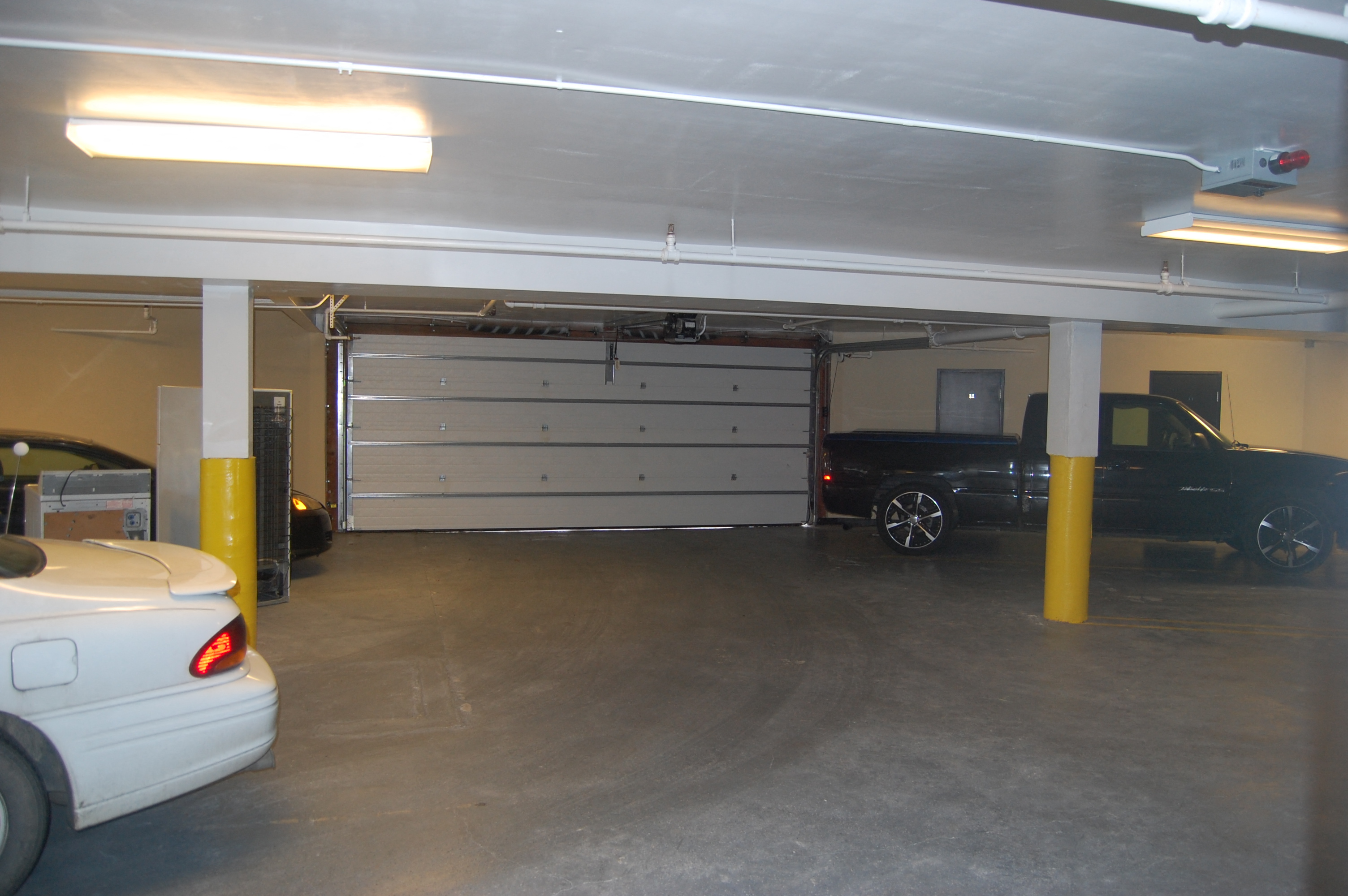 a garage with a white door and cars parked in it