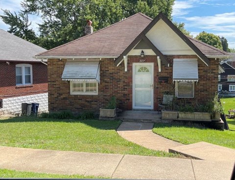 A small brick house with a white door and windows.