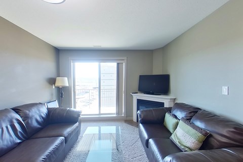 A living room with a brown leather couch and a television on a stand.