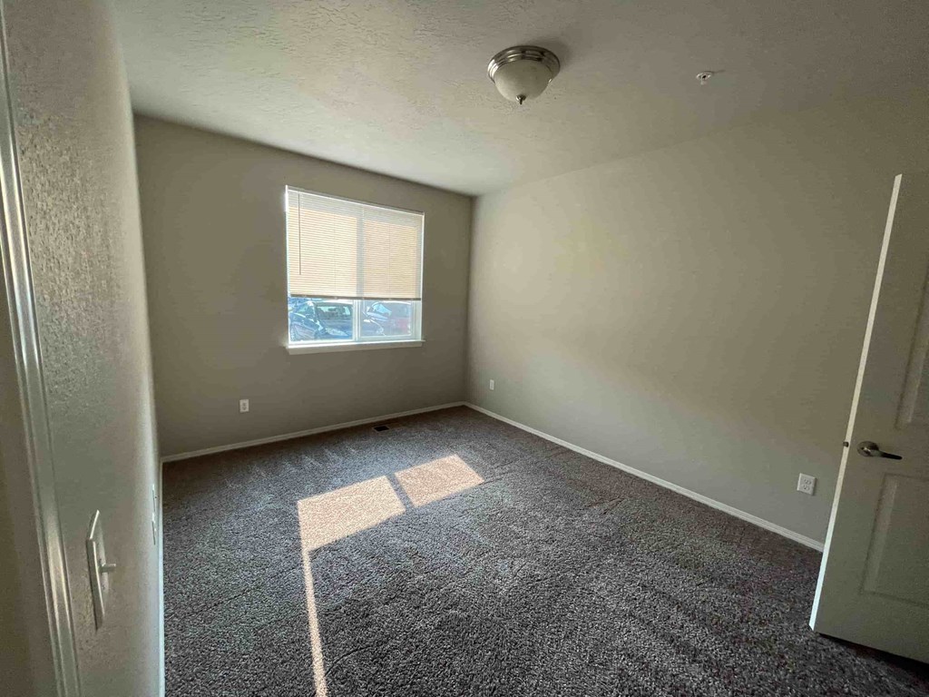 an empty room with gray carpet and a window