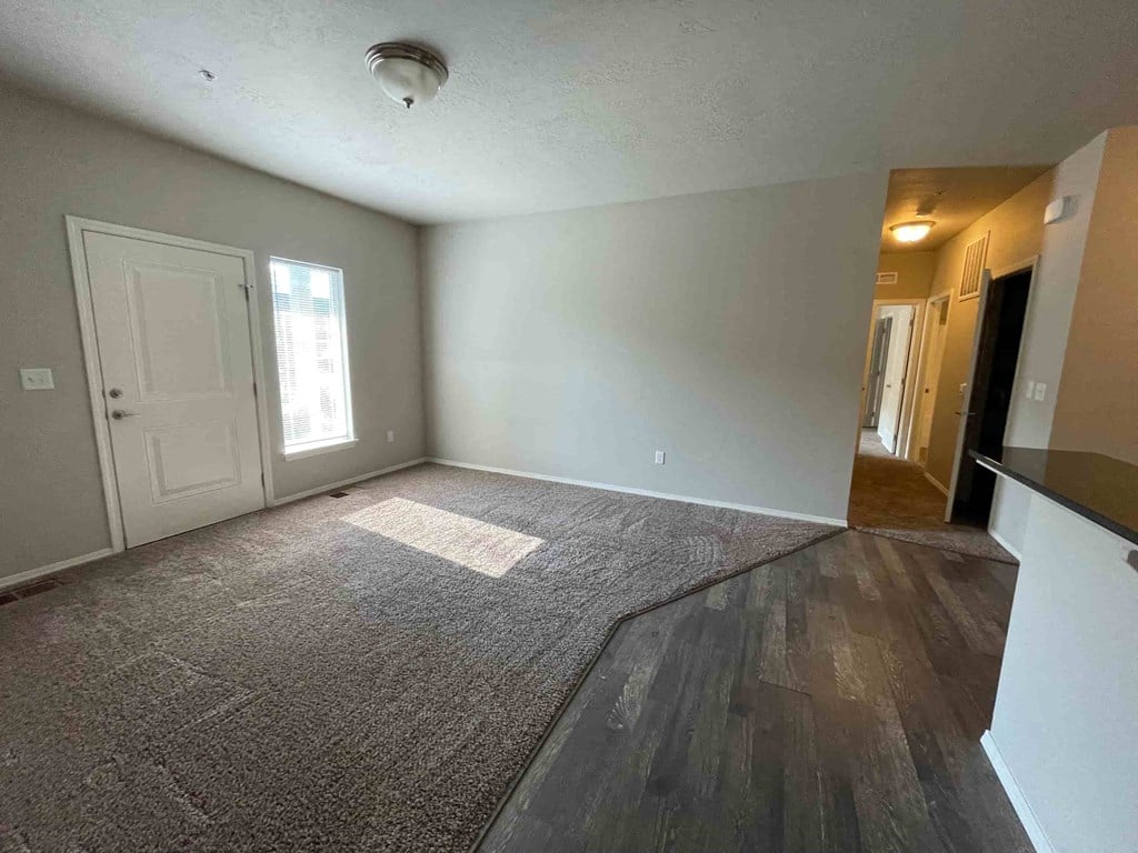 an empty living room with a white door and wood flooring