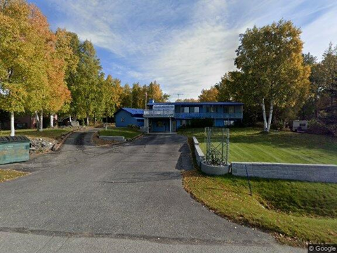 A blue building is surrounded by trees with autumn leaves.