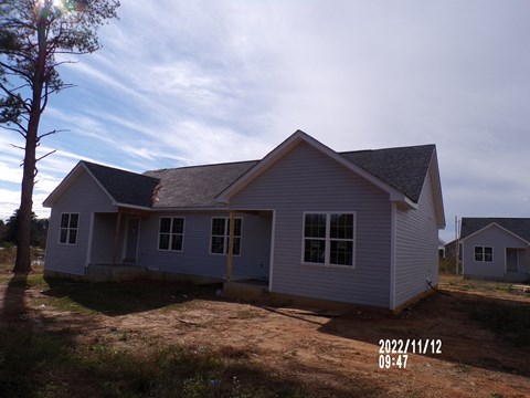 A small house with a grey roof and white walls is shown in the image.