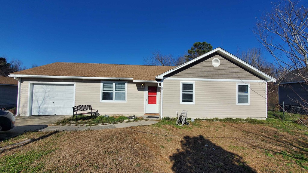 a renovated home with a red door and a white garage