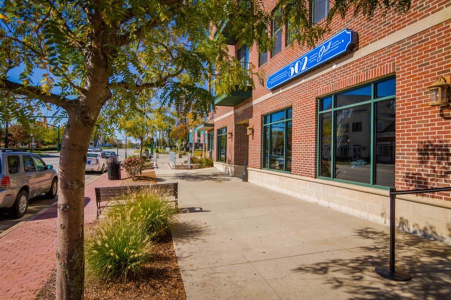 a sidewalk in front of a brick building with a blue street sign