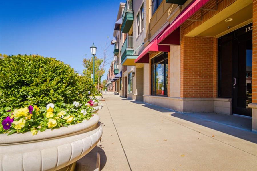 a sidewalk with large planters with flowers on it
