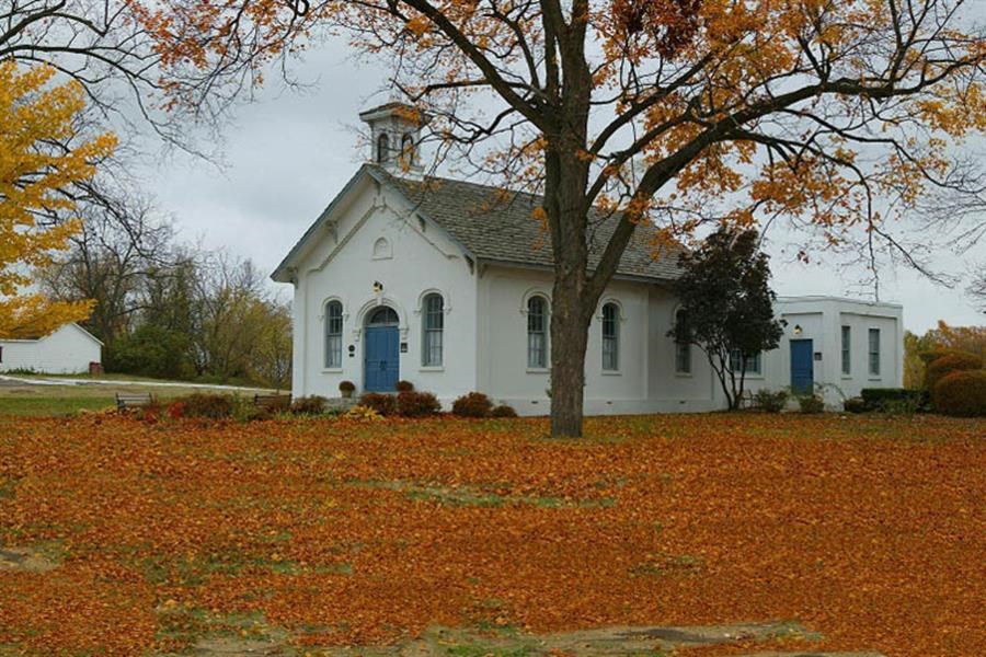 a white church with blue doors and a tree