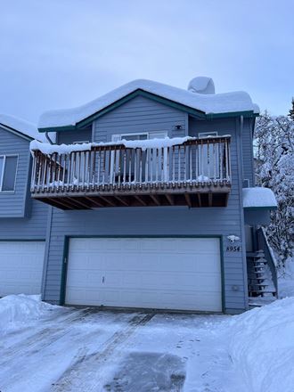a house with a balcony and a garage door in the snow