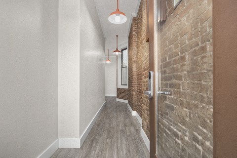 a long hallway with a brick wall and wooden doors