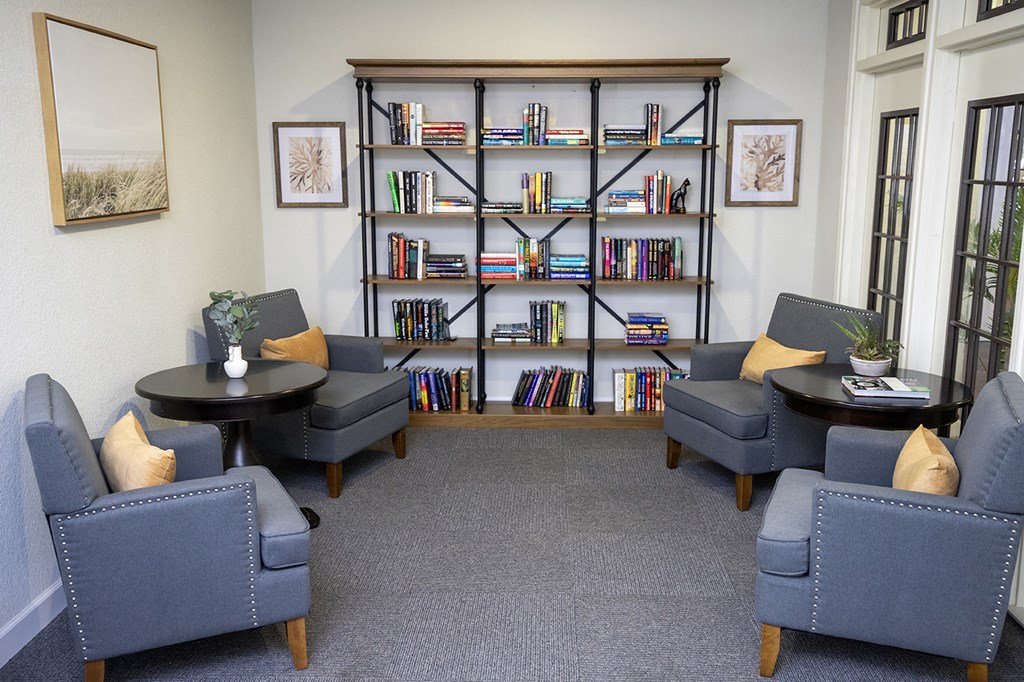 A room with a bookshelf and four chairs.