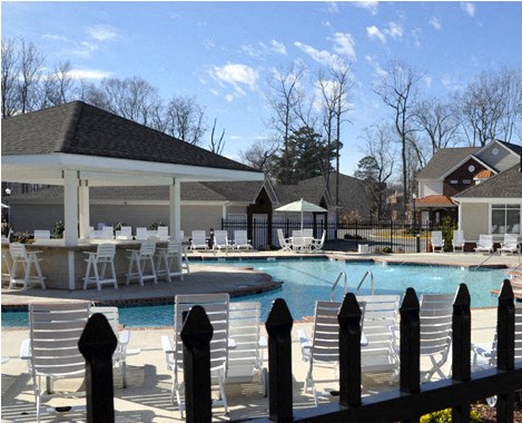 a swimming pool with chairs and tables around it