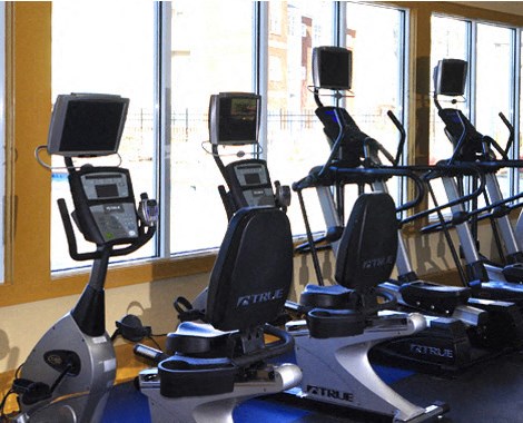 a group of exercise equipment in a gym with windows
