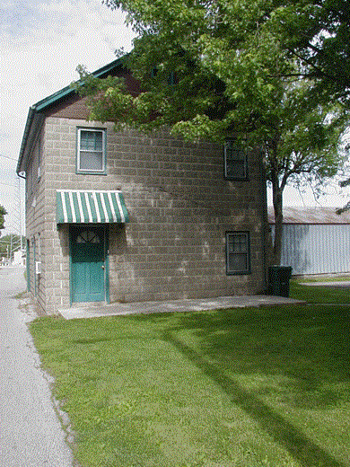 an old brick building with a green door and a tree