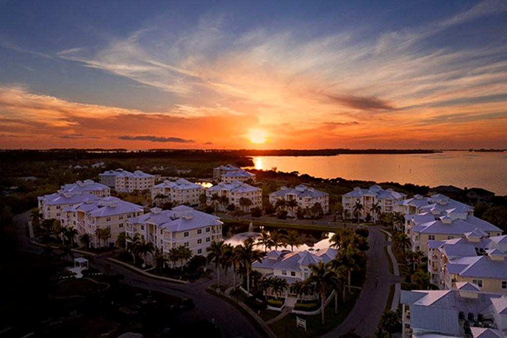 an aerial view of the resort with the sun setting over the water