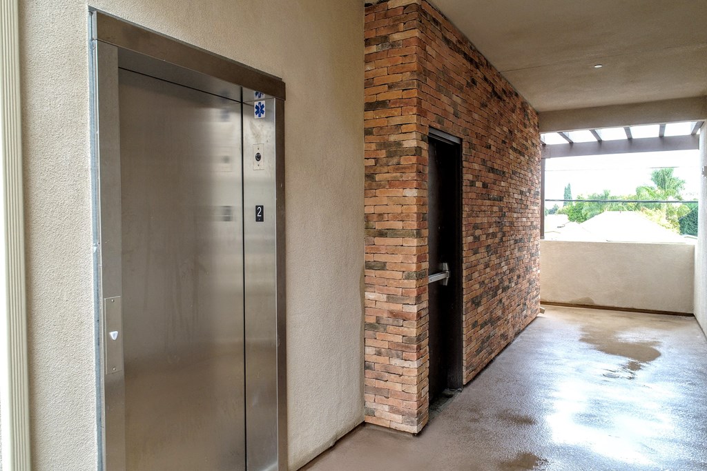 an empty room with a door and a brick wall