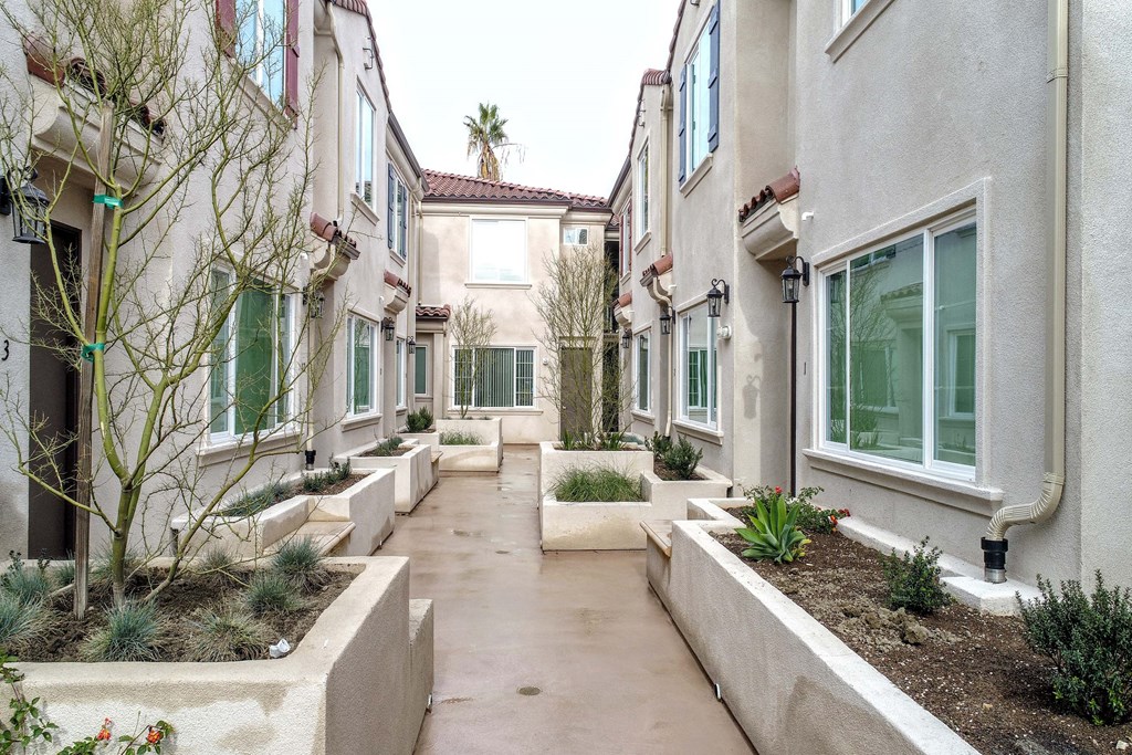 a street view of an apartment building with plants