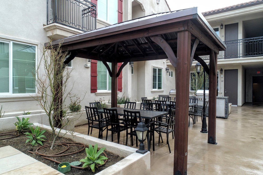 a patio with tables and chairs under a wooden pavilion