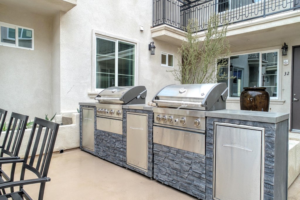 an outdoor kitchen with two barbecue grills on a patio