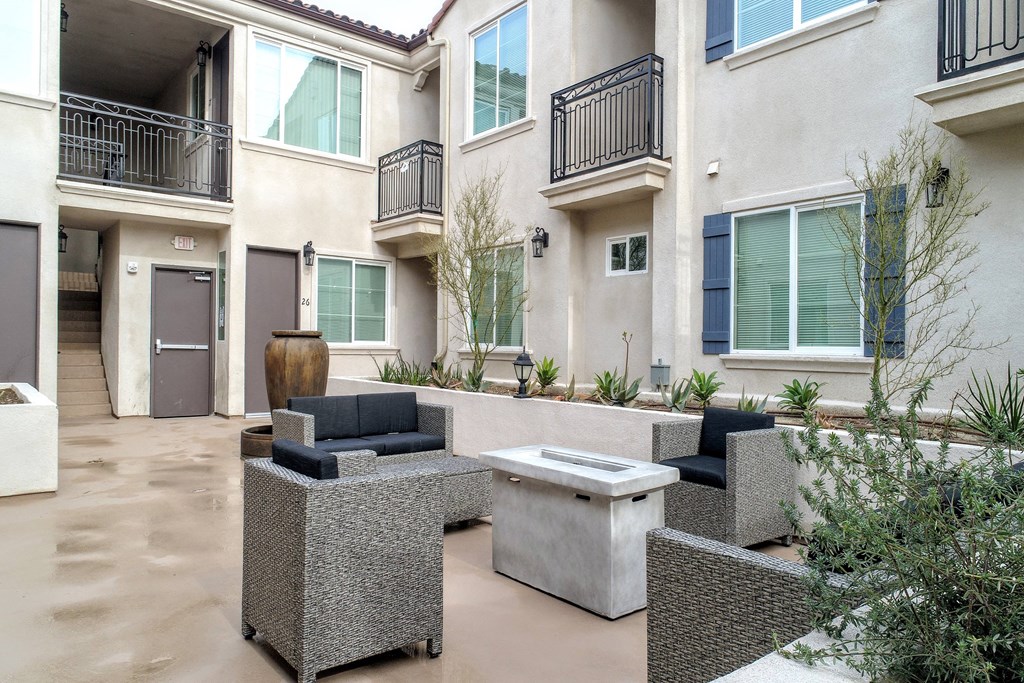 a patio with a fire pit in front of an apartment building