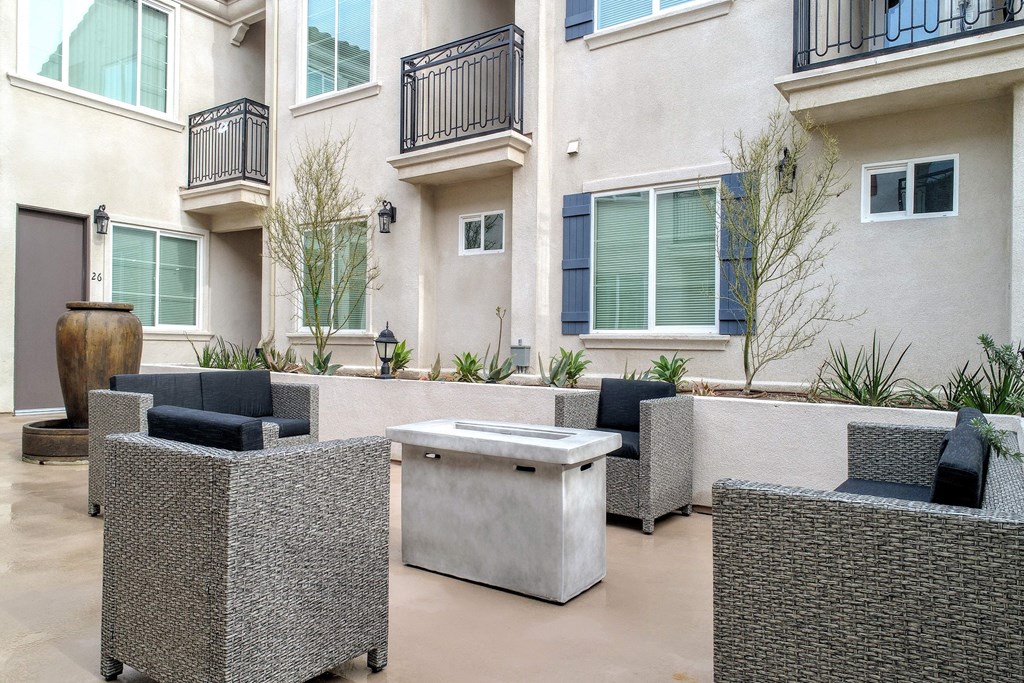an outdoor patio with chairs and a table in front of an apartment building