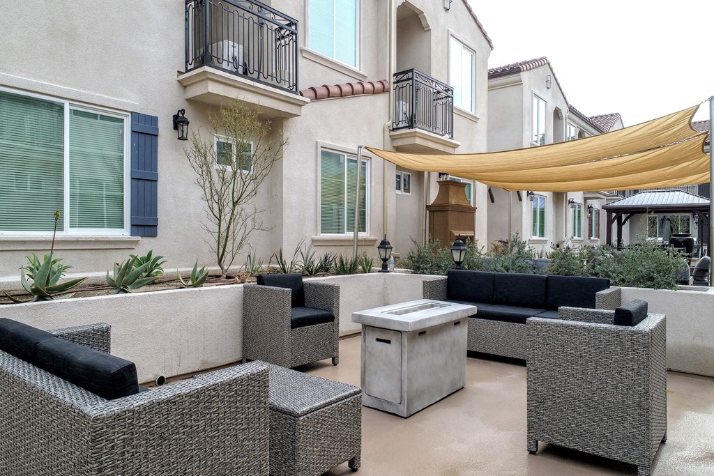 a patio with couches and tables in front of a house