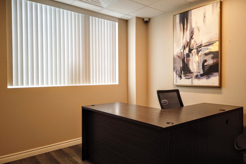 an office with a desk and a painting on the wall