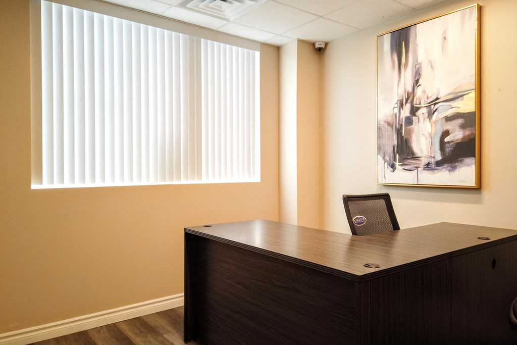 an office with a desk and a painting on the wall