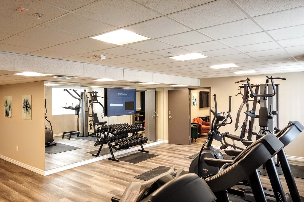 a gym with exercise equipment and a tv in the ceiling