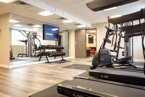 a gym with cardio equipment and a tv in a room