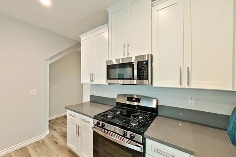 a kitchen with white cabinets and a stove and microwave