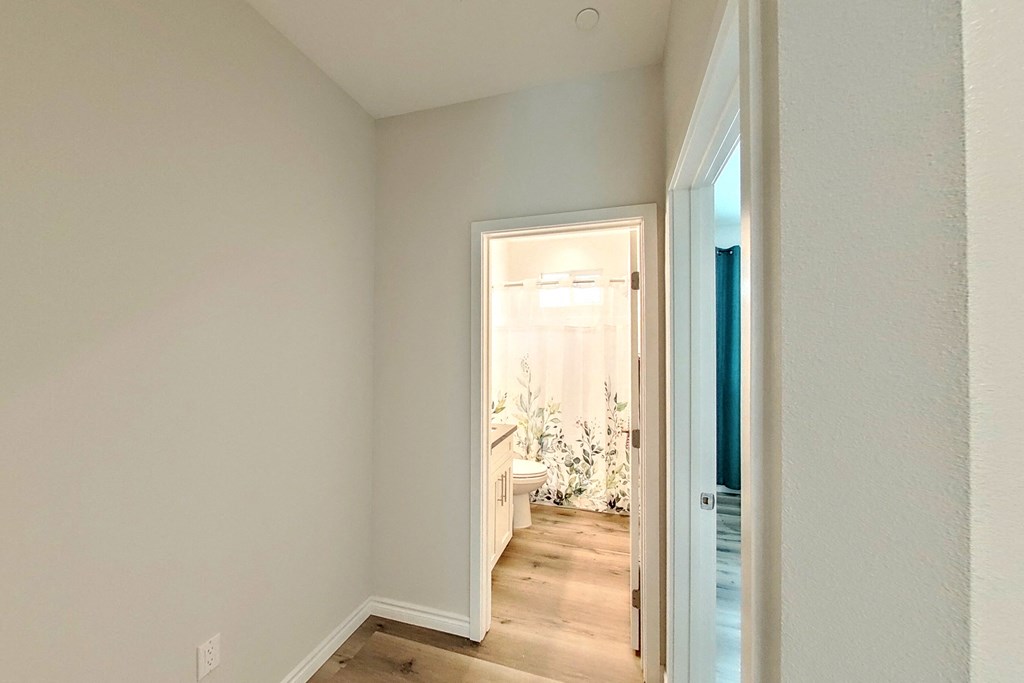 a corridor with a door to a bathroom and a door into a bedroom