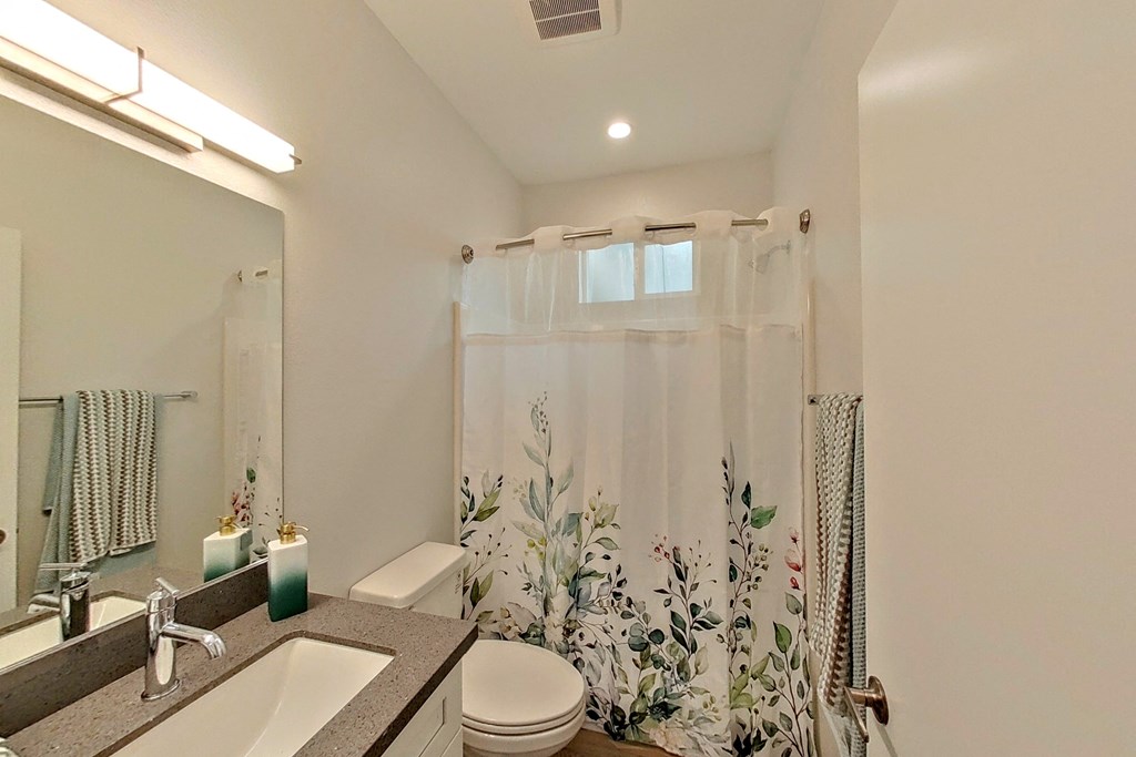 a bathroom with a shower curtain and a sink and a toilet