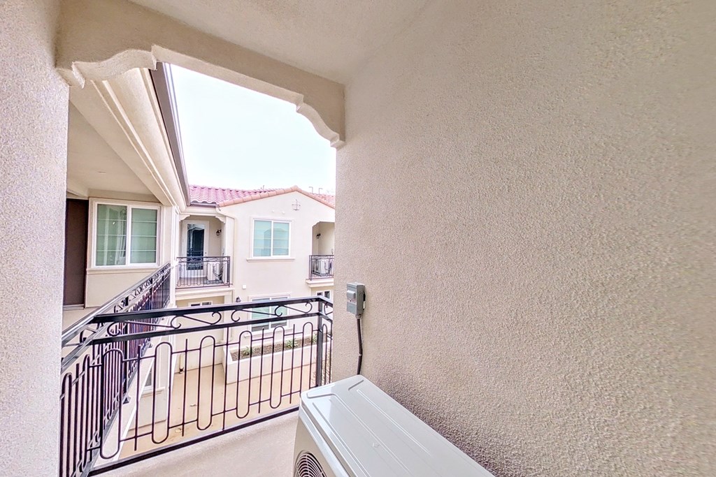 a balcony with a gate and a house in the background