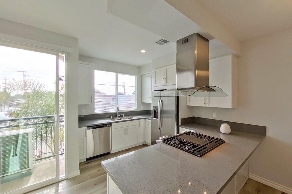 a kitchen with white cabinets and a counter top with a stove and a refrigerator