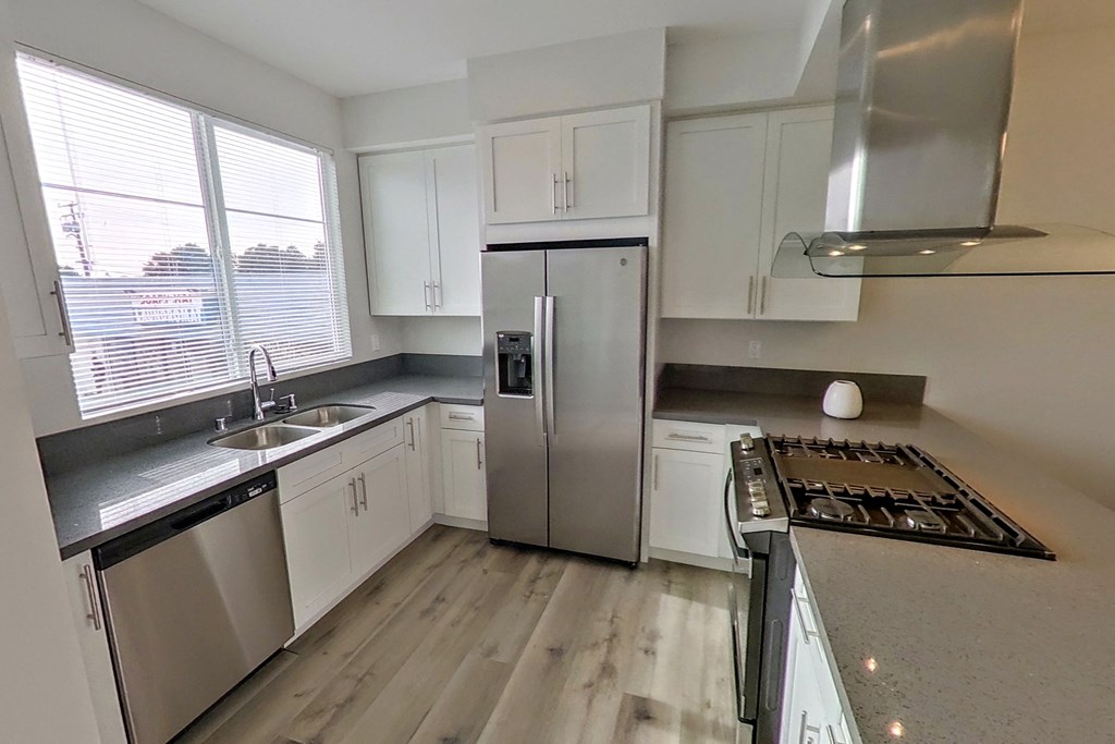 an empty kitchen with stainless steel appliances and white cabinets