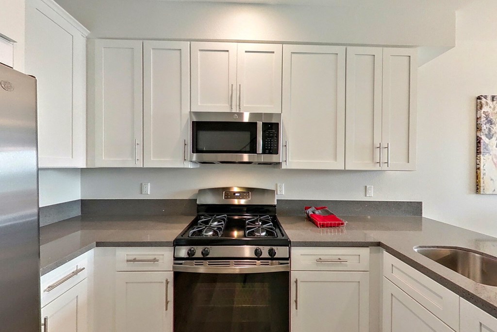 a white kitchen with stainless steel appliances and white cabinets
