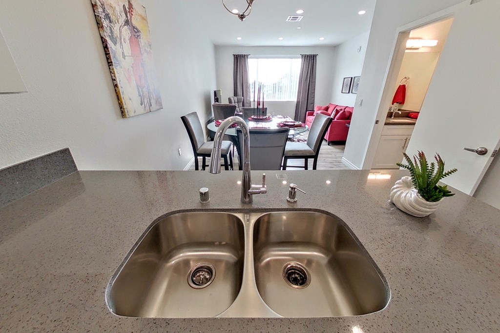 a kitchen sink with a view of a living room and dining room