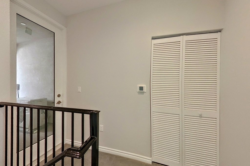 a closet in a room with a staircase and a door to a bathroom